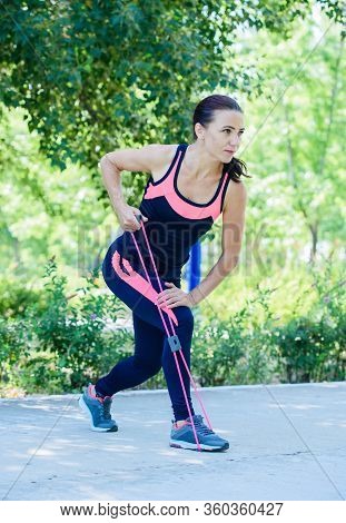 A Girl In Nature Is Engaged In Sports With The Help Of An Espander.
