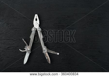 Multi-functional Tool On A Black Textural Background.