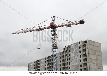 Construction Crane On The Background Of A Standing Panel Building.
