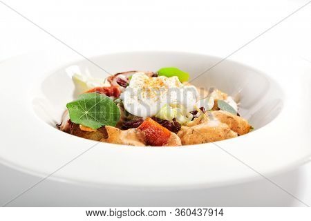 Salad in white bowl. Sliced octopus and fried potato. Served cut ingredients with mayonnaise, tomato spicy ajika and smoked pepper homemade sauce. Restaurant food portion in plate close up