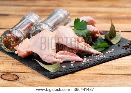 Raw Chicken Wings With Spices On A Black Cooking Board And On A Wooden Background. Fresh Chicken Win