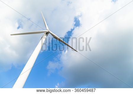 Wind Turbine Against A Cloudy Blue Sky