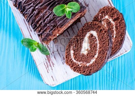 Cocolate Roll With White Fillings On A Blue Background. Desert Sweet Food