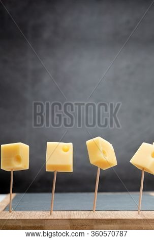 Portions (cubes, Dice) Of Emmental Swiss Cheese Punctured In Toothpicks. Copy Space.
