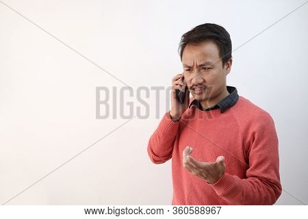 A Man Talking Over The Phone In An Angry Unhappy Mood Isolated In White Background With Space For Te