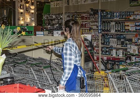 . Manitowoc, Wi Usa April 9 2020: The Girl Spraying Protective Spray And Disinfecting Shopping Carts