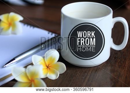 Coffee Cup With Text - Work From Home, With Bali Frangipani Flowers, Pen And Notebook On Desk. Socia