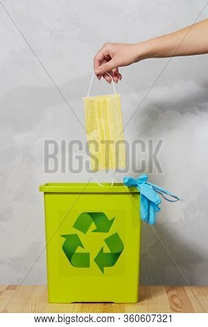 End Of Coronavirus Quarantine. A Female Hand Throws Used Face Masks Into A Trash Can. Return To Norm