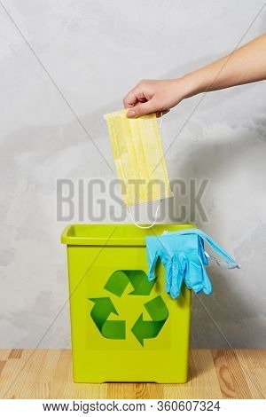 End Of Coronavirus Quarantine. A Female Hand Throws Used Face Masks Into A Trash Can. Return To Norm