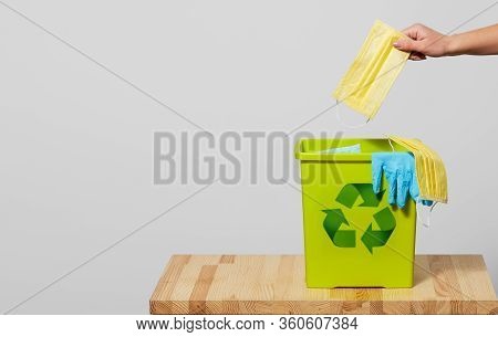 End Of Coronavirus Quarantine. A Female Hand Throws Used Face Masks Into A Trash Can. Return To Norm