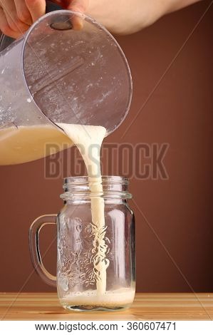 Milkshake Making On Wooden Table Closeup. Process Of Topping And Decorating Milkshake. Desset With C