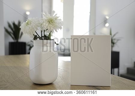 On The Table Is A Mockup Of A Flowers  And A White Book. Coffee House. Cafe Background. Flowers Whit