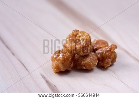 closeup of some nueces de macadamia garrapinadas, spanish candied macadamia nuts, on a wooden table