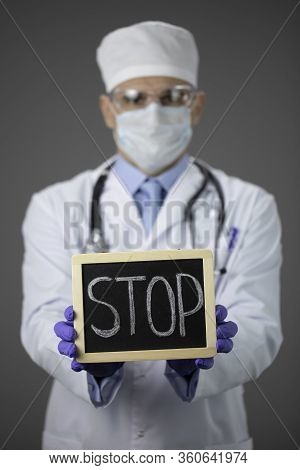 Male Doctor In Medical Uniform, Stethoscope, Protective Mask And Glasses Holding Stop Sign In Hands.