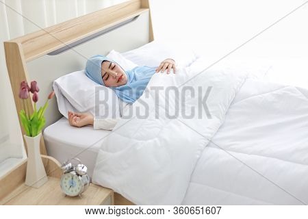 Oversleeping Asian Muslim Woman Wearing White Sleepwear Lying On Bed With Happiness.top View Portrai