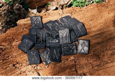 24 Norse Runes Stones On Old Wood Background. The Play Of Light And Shadow.