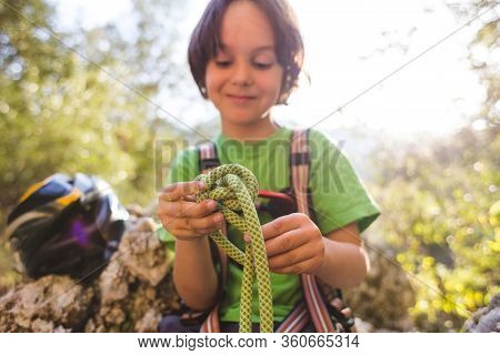 A Child Learns To Knit The Safety Knot From The Rope.