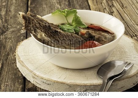 Shorpo In A White Plate With A Piece Of Beef Meat In A Broth With Vegetables On A Wooden Stand, A Sp