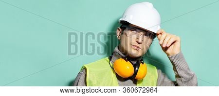 Portrait Of Young Construction Engineer Worker Wearing Safety Helmet, Goggles, Jacket And Headphones