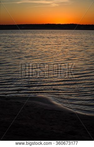 Late Evening River Sunset View With Small Waves On The Water And Orange-yellow Sky. Photo Taken In L