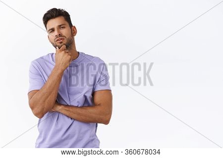Thoughtful Young Man Picking Something In Store, Touching Chin Pensive Squinting, Considering What C