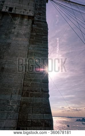 Sun Behind The Brooklyn Bridge Pilon And Cables In New York