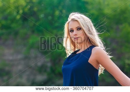 Young Beautiful Blond Woman In Blue Mini Dress And Floral Wreath Standing And Trying Water On Summer