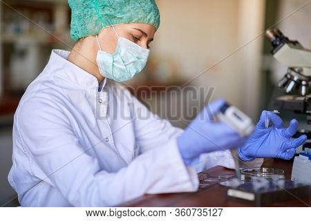Female lab tehnician with protective gear working in lab