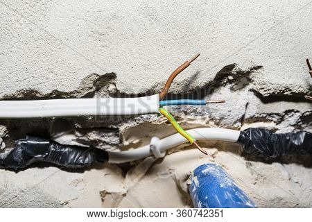Cut Single-phase Cable In The Wall Of The House. Phase, Neutral And Ground Wire Visible.
