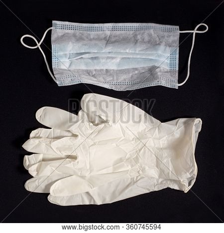 Pair Of Latex Medical Gloves And Ear-loop Mask On Black Background. Protection Concept