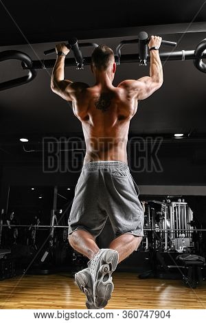 The Athlete Does A Pull-up On The Horizontal Bar. A Man In Great Shape Is Doing Pull-ups On The Hori