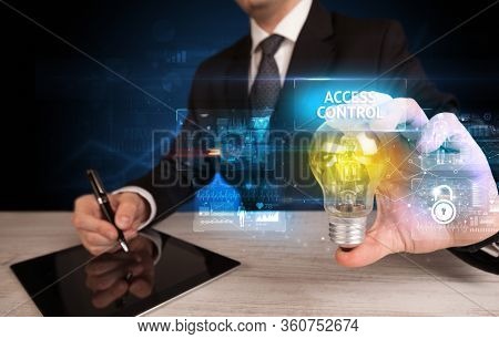 Businessman holding lightbulb with ACCESS CONTROL inscription, online security idea concept