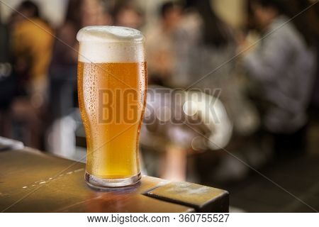 Glass of beer stands on a table in a pub. White unfiltered beer.