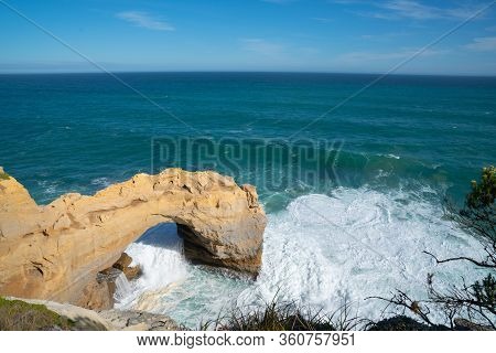 Coastal Natural Arch Viewed From Adjacent Cliffs With Waves Crashing Around On Great Ocean Road, Vic