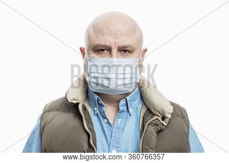 Bald Adult Man In A Medical Mask On A White Background. Close-up. Precautions Quarantined For The Pe