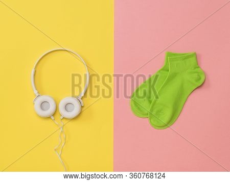 Green Sports Socks And White Headphones On A Pink And Yellow Background. The Color Trend. The Concep