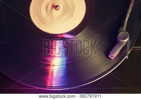 Retro Record Player With A Spinning Black Vinyl Record Reflecting Color Lights