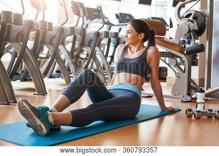 Happy To Be Healthy Cheerful Sporty And Young Woman In Sportswear Is Sitting On The Map At Gym And S