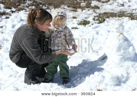母亲和儿子玩雪和建设一个雪人