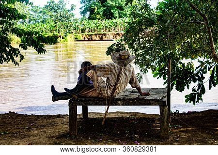 Peasant Man Sitting With His Grandson On The Banks Of The River, Etcr Brisas, Choco, Colombia.