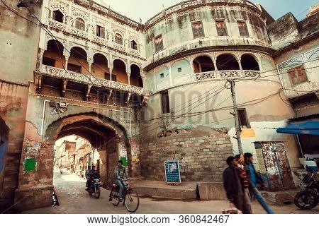 Shekhawati, India: Small Town Street Under Historical House Arch And Bikes In Motion Driving Past On