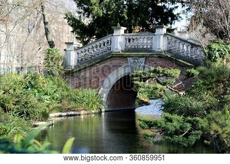 Beautiful Old Stone Bridge With Railing Over Clean River In Preserve. Natural Nature Consisting Of A