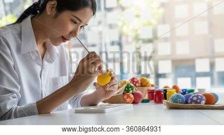 Happy Asian Woman Painting Eggs For Eastertime At Home. Family Preparing For Easter.