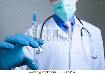 Close Up View Of Medical Syringe In Rubber Blue Glove Dressed Hand, Man Chest In White Medical Robe 