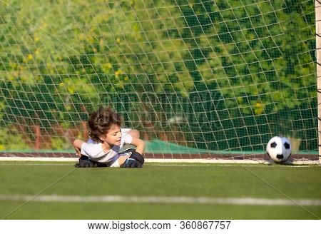 Junior Soccer Goalkeeper. Disappointed Boy In White Goalie Sportswear. Goalkeeper Missed A Goal Duri