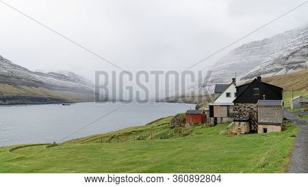 Bour, Faroe Islands - August 2019: A Small Settlement Village Overlooking A Fjord Surrounded By Gree