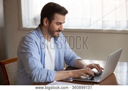 Handsome Pleasant Young Man Working Remotely On Computer At Home.