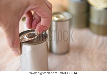Hand Open Canned Food In Metal Can On Wooden Background / Close Up Canned Goods Non Perishable Food 