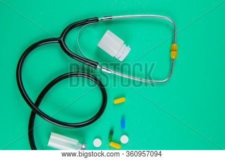 Studio Shot Of Stetoscope, Syringe And Pills On Light Green Background. Top Views.