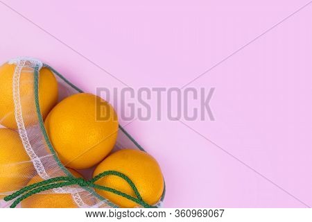 Oranges In Mesh Bag Flat Lay On Pink Background